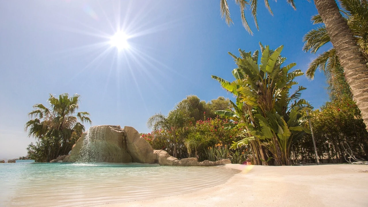Piscina de arena Arelite Classic integrada en un entorno tropical