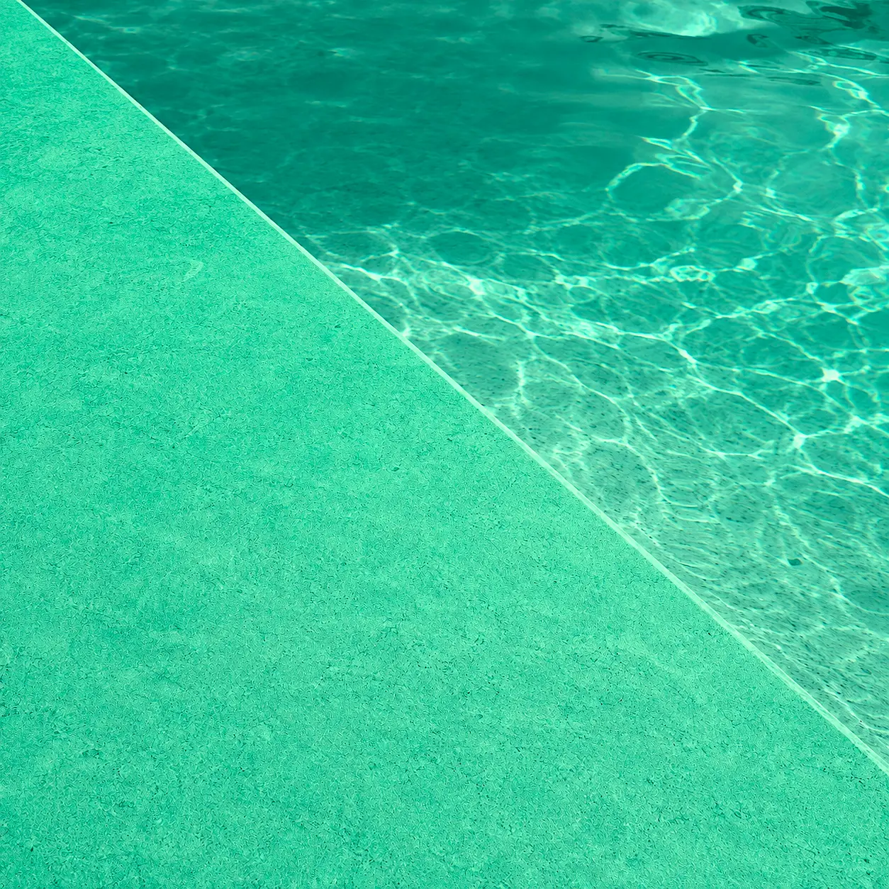 Detalle del acabado Arelite Marfe Bermuda en una piscina, con superficie continua en tono verde agua y acabado mineral.