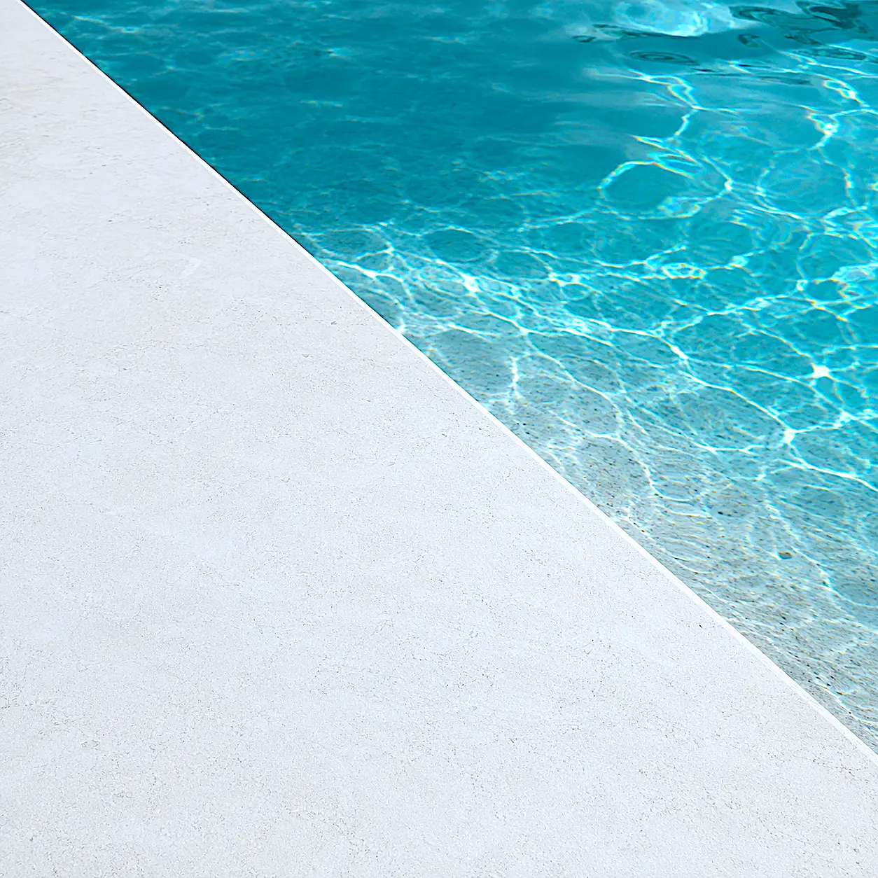 Detalle del acabado Arelite Marfe Blanco en una piscina, con superficie continua en tono blanco y agua azul clara.