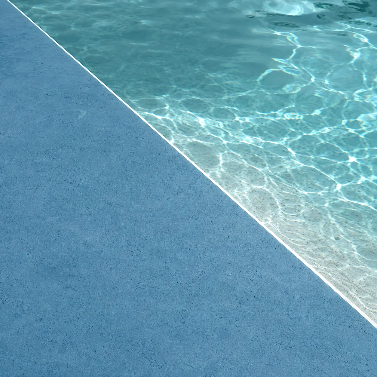 Detalle del acabado Arelite Marfe Marine en una piscina, con superficie continua en tono azul medio y agua clara.