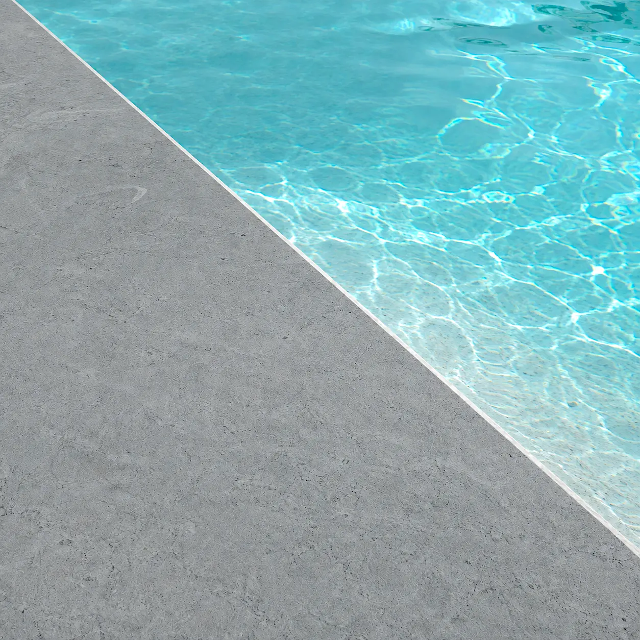 Detalle del acabado Arelite Marfe Onix en una piscina, con superficie continua en tono gris antracita y agua azul.