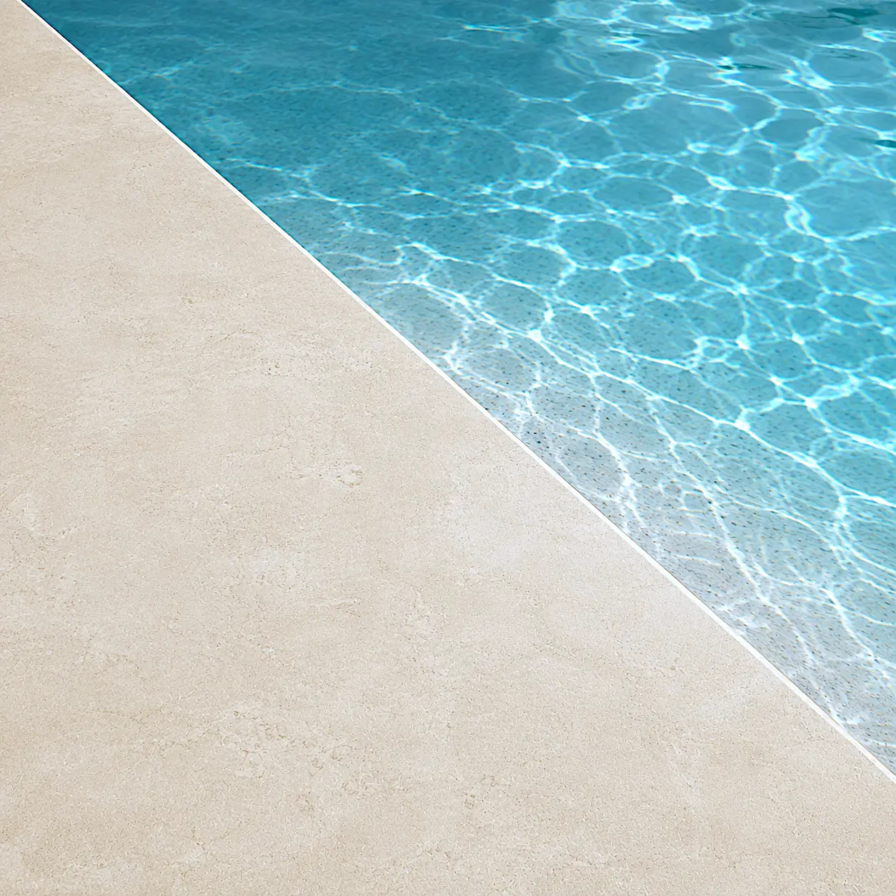 Detalle del acabado Arelite Marfe Sand en una piscina, con superficie continua en tono arena suave y agua cristalina.