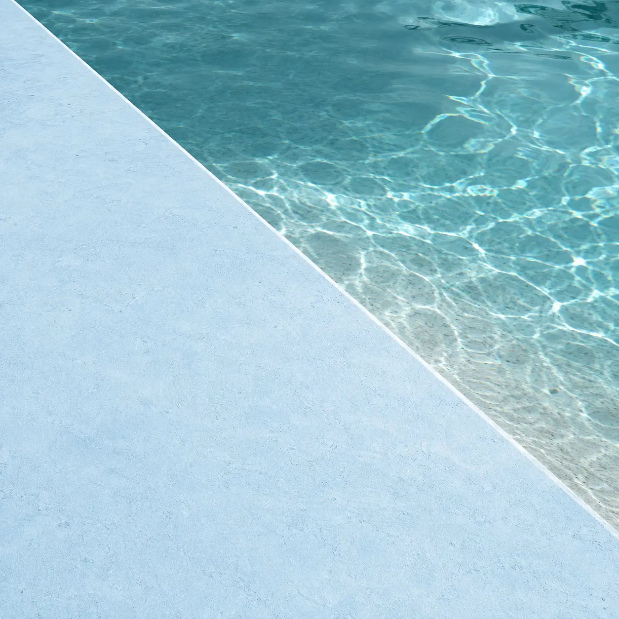 Detalle del acabado Arelite Marfe Sky en una piscina, con superficie continua en tono azul claro y agua brillante.
