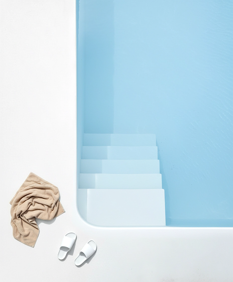 Piscina de líneas limpias con acabado mineral continuo y escalera integrada bajo el agua